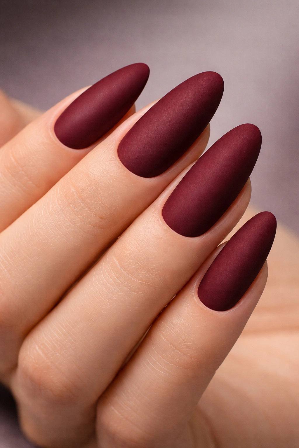 Close-up of a matte burgundy oval nail