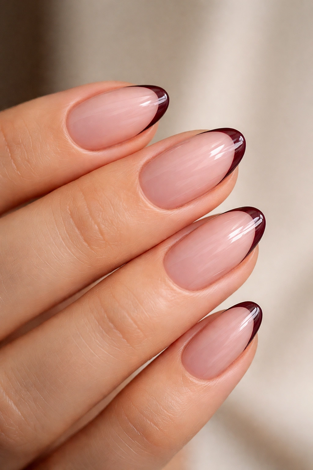 Close-up of short almond nails with burgundy micro-French tips