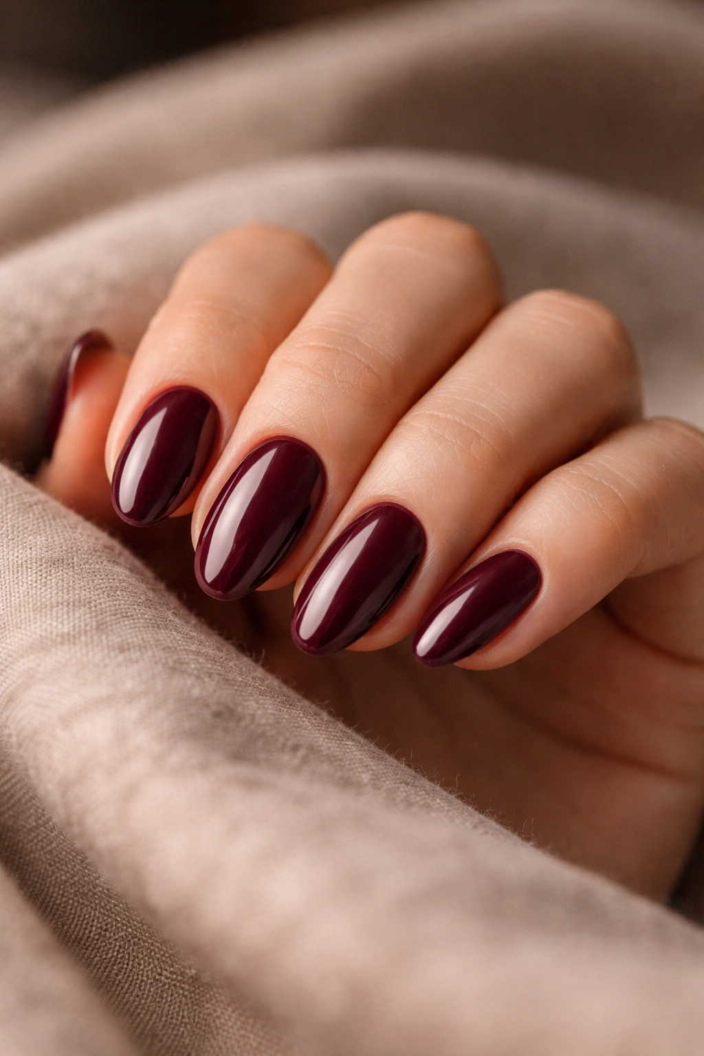 Close-up of deep burgundy short almond nails with crème finish