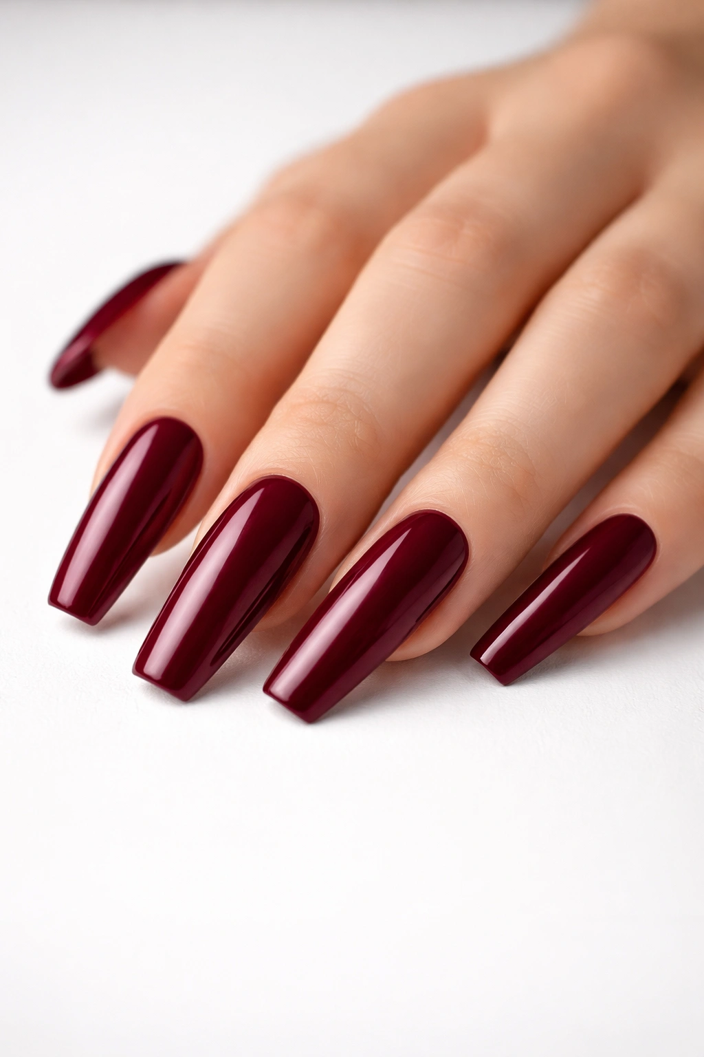 Close-up of long coffin nails with a glossy solid burgundy color, no embellishments