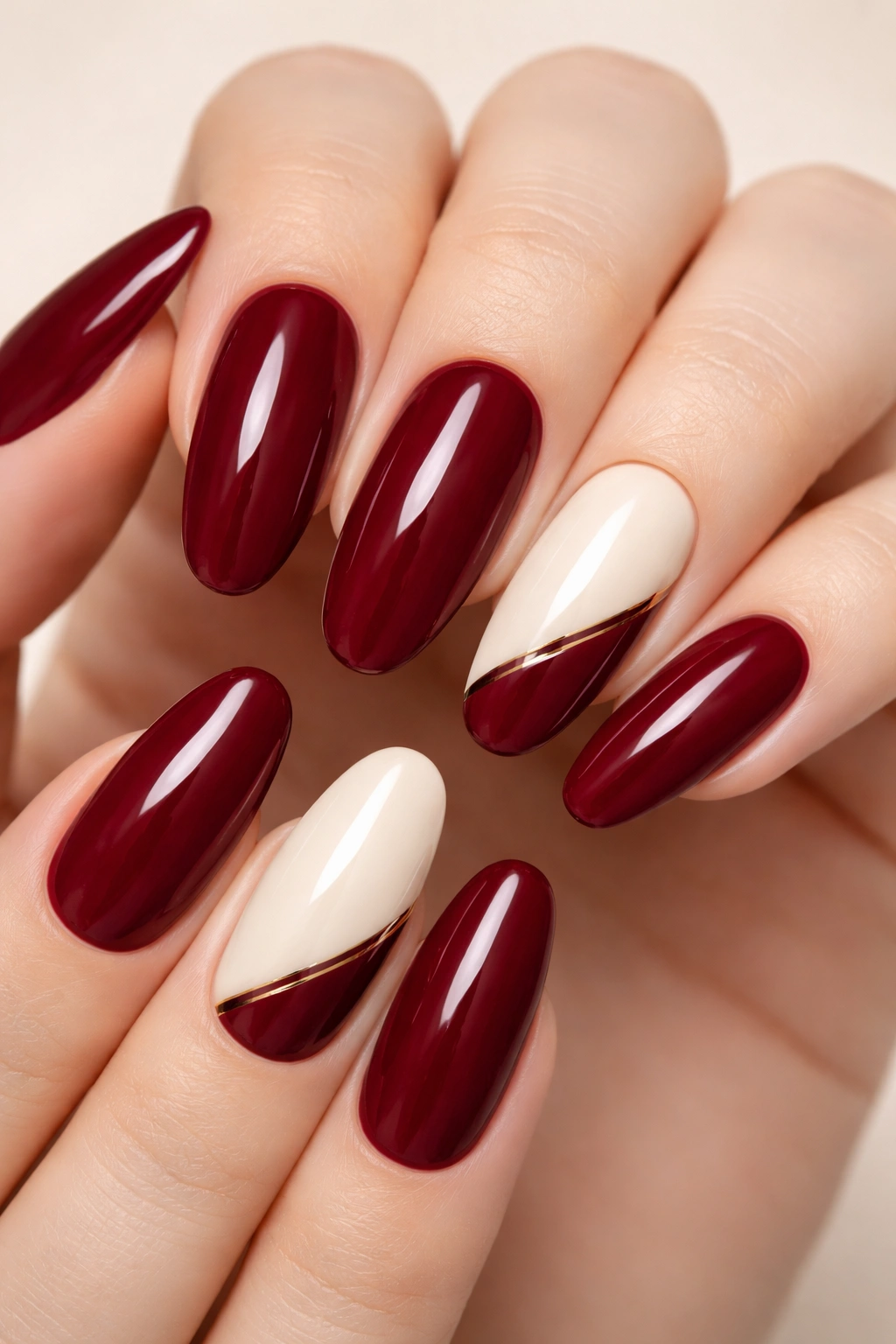 Close-up of long round nails in burgundy red with cream accent nails
