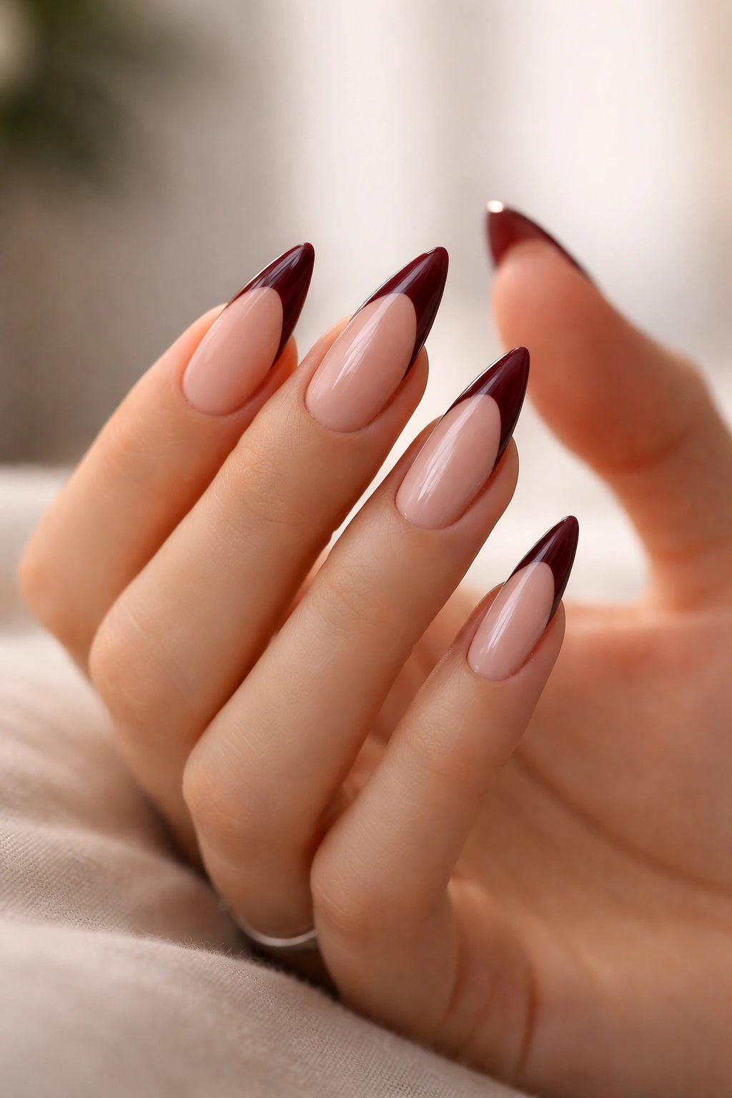 Close-up of hand with burgundy stiletto nails in contemplation