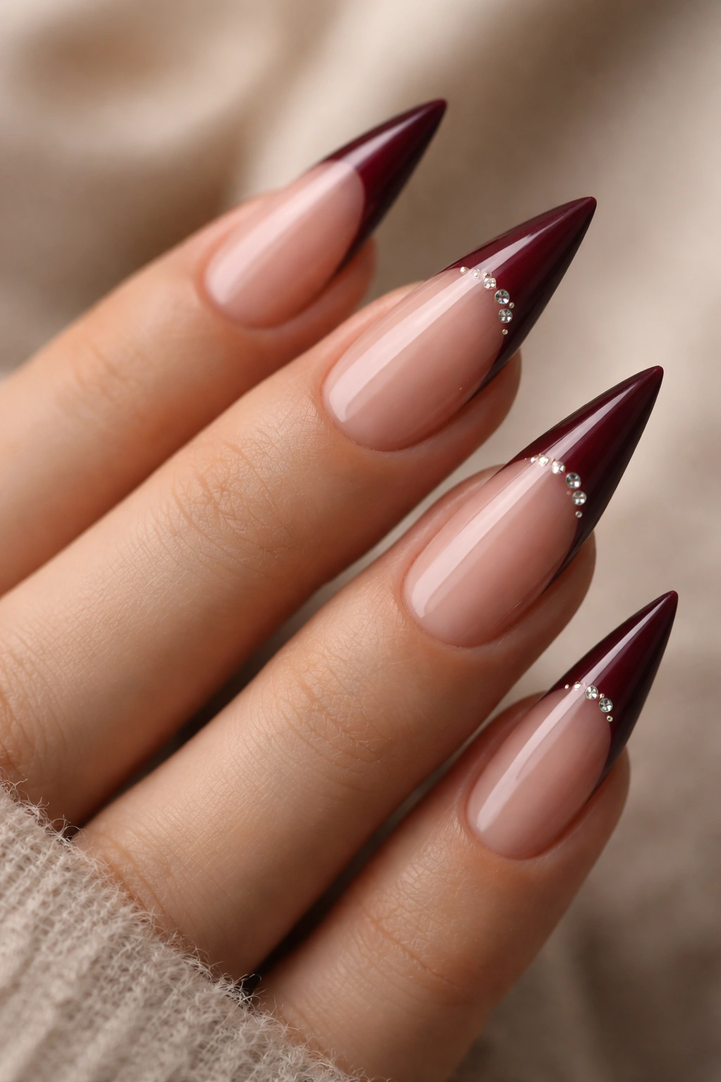 Close-up of burgundy nails with small rhinestones near the tip