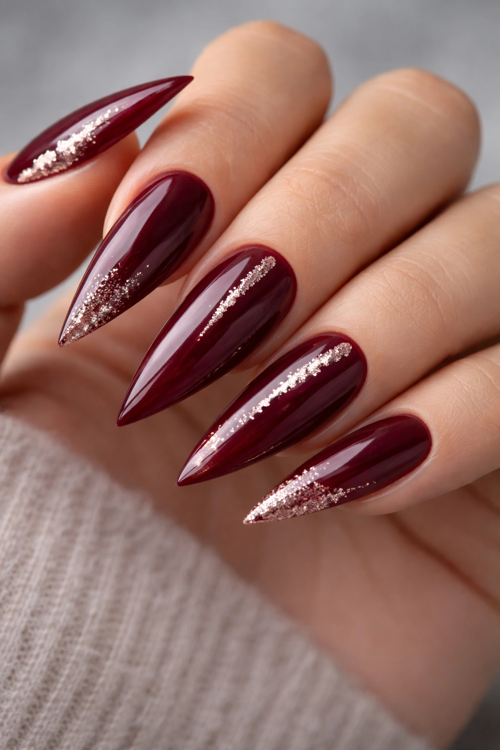 Burgundy stiletto nails with strategic glitter accents.