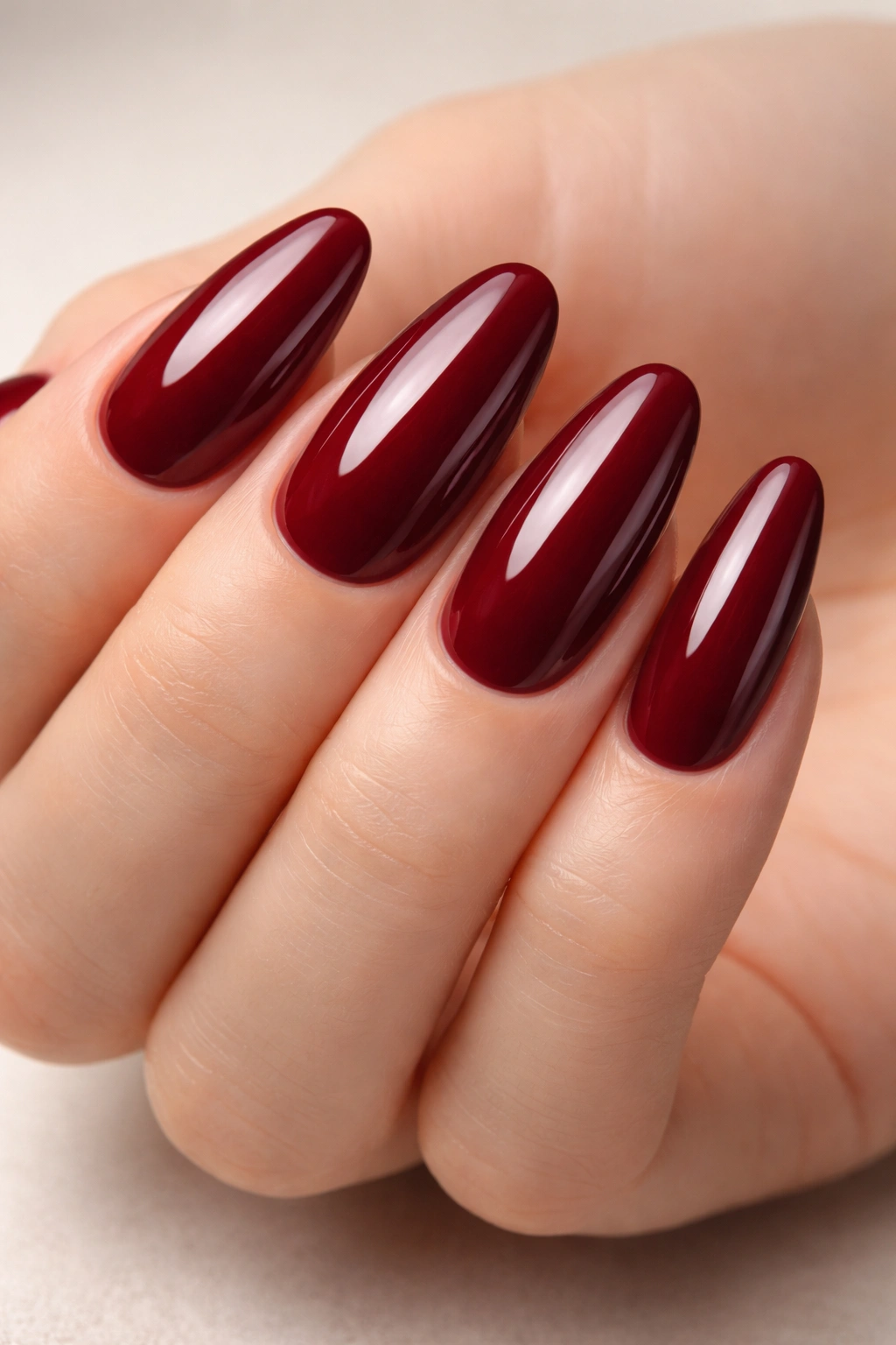 Close-up of long oval burgundy nails with a high-gloss topcoat