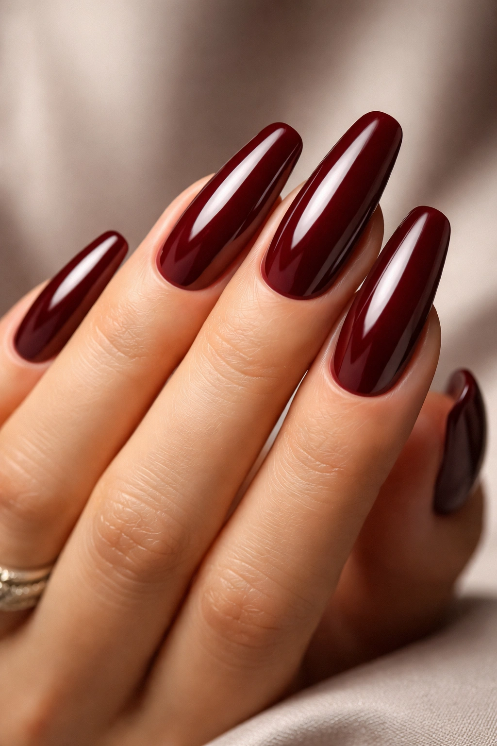 Close-up of glossy burgundy nails with liquid-like shine on a skin-toned hand