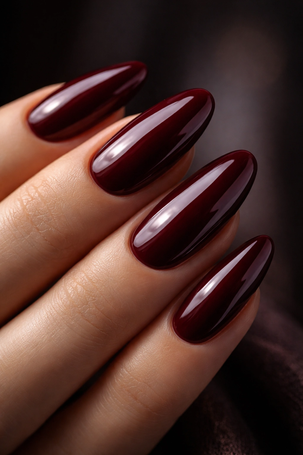 Close-up of deep burgundy long oval nails with high-gloss finish