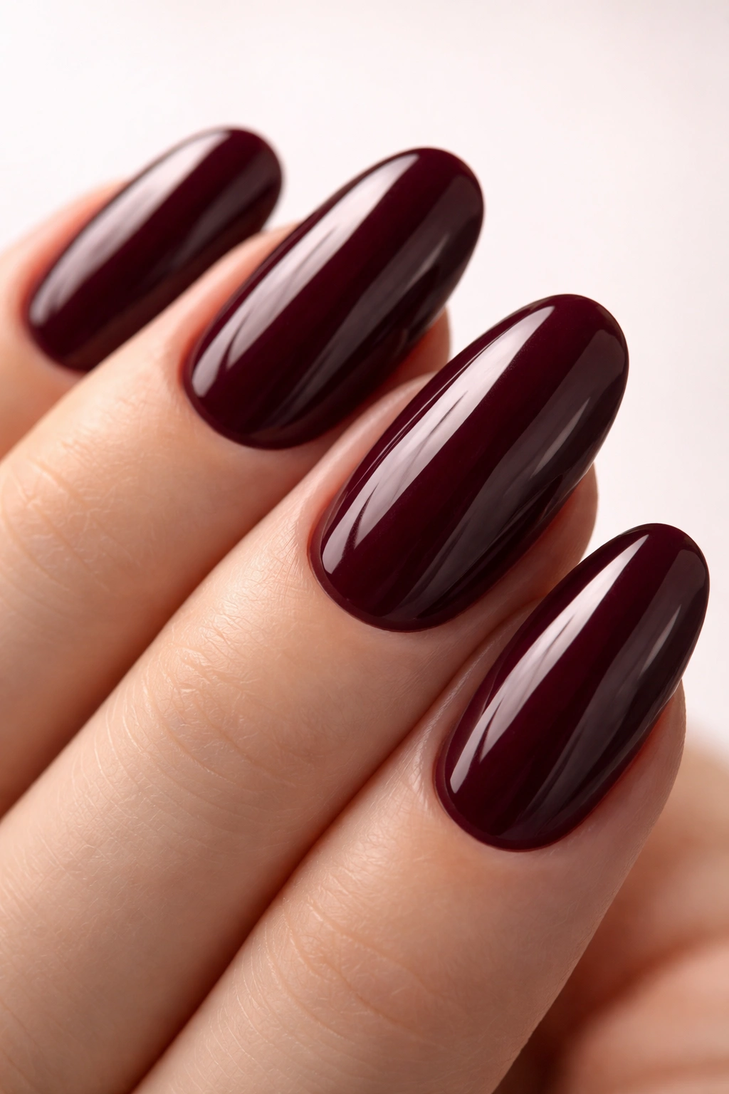 Close-up of long round nails in deep burgundy with glossy gel finish