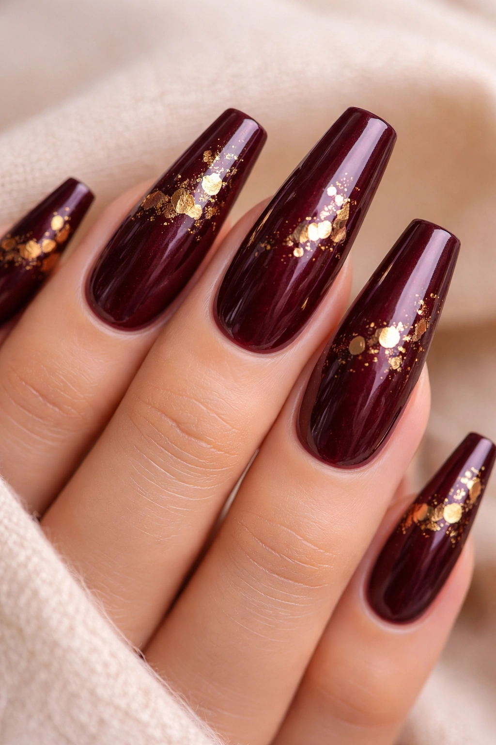 Close-up of burgundy coffin nails with small gold foil flecks