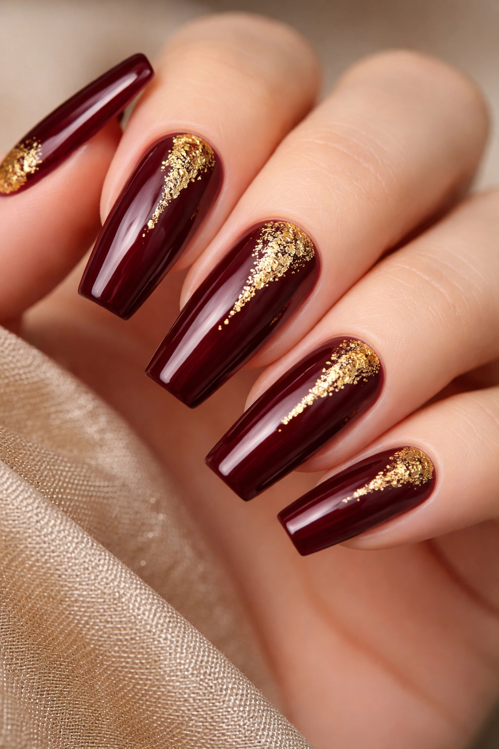 Close-up of burgundy coffin nails with gold leaf accents