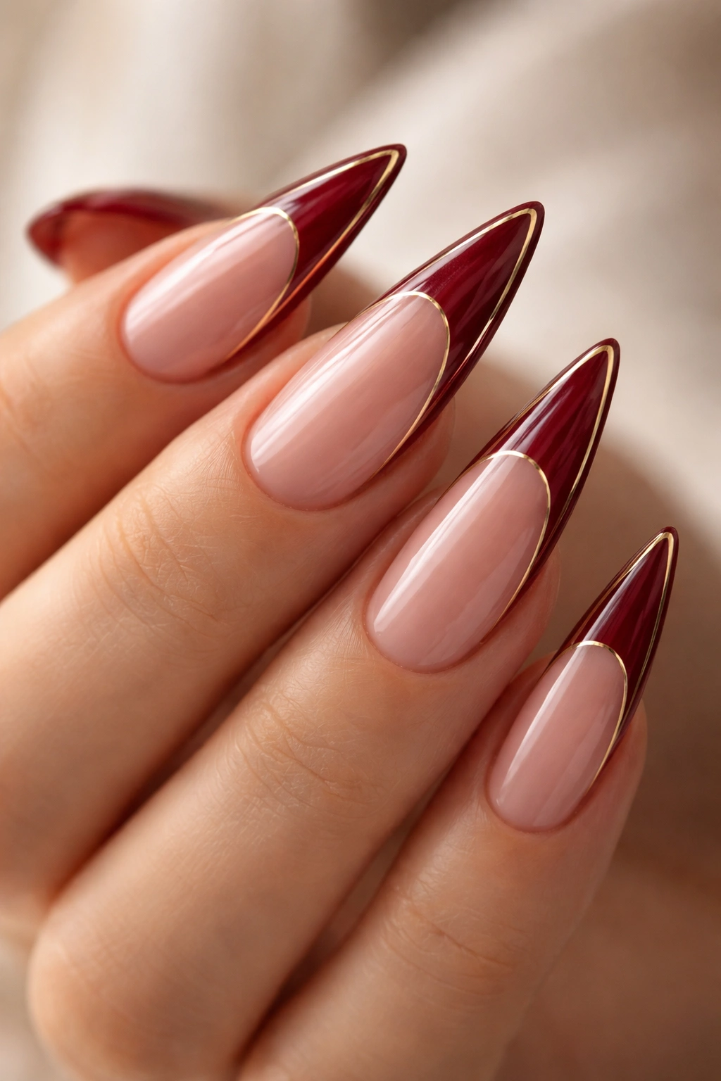 Close-up of burgundy French tips with a thin gold outline on nails