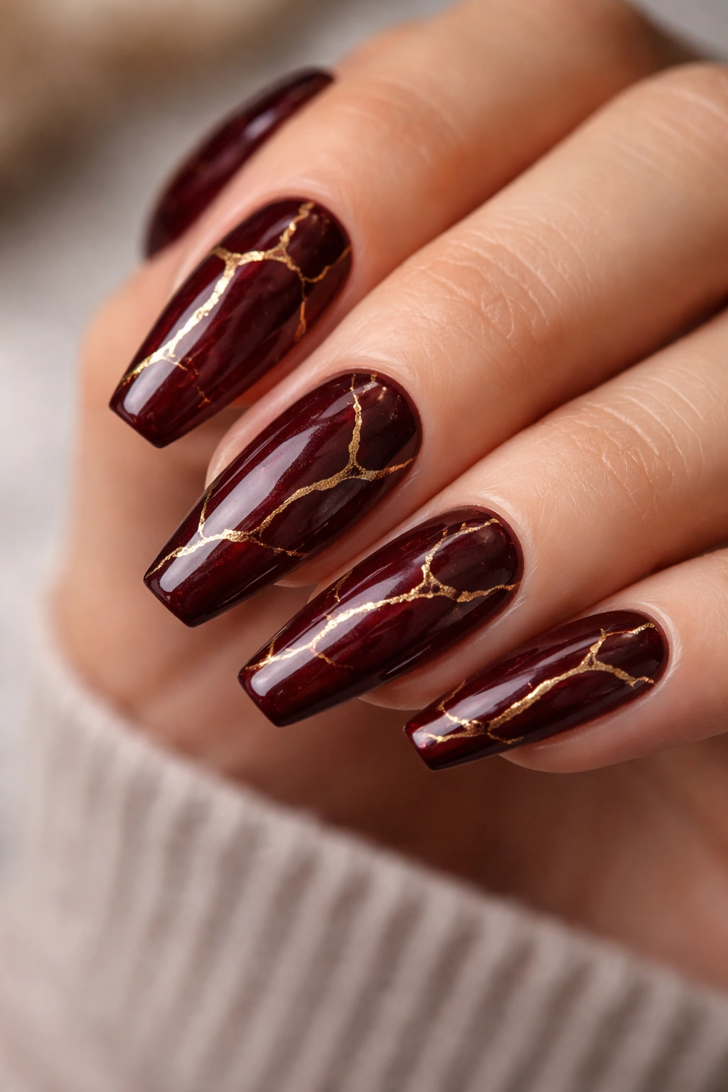 Close-up of medium coffin nails in deep burgundy with gold veining