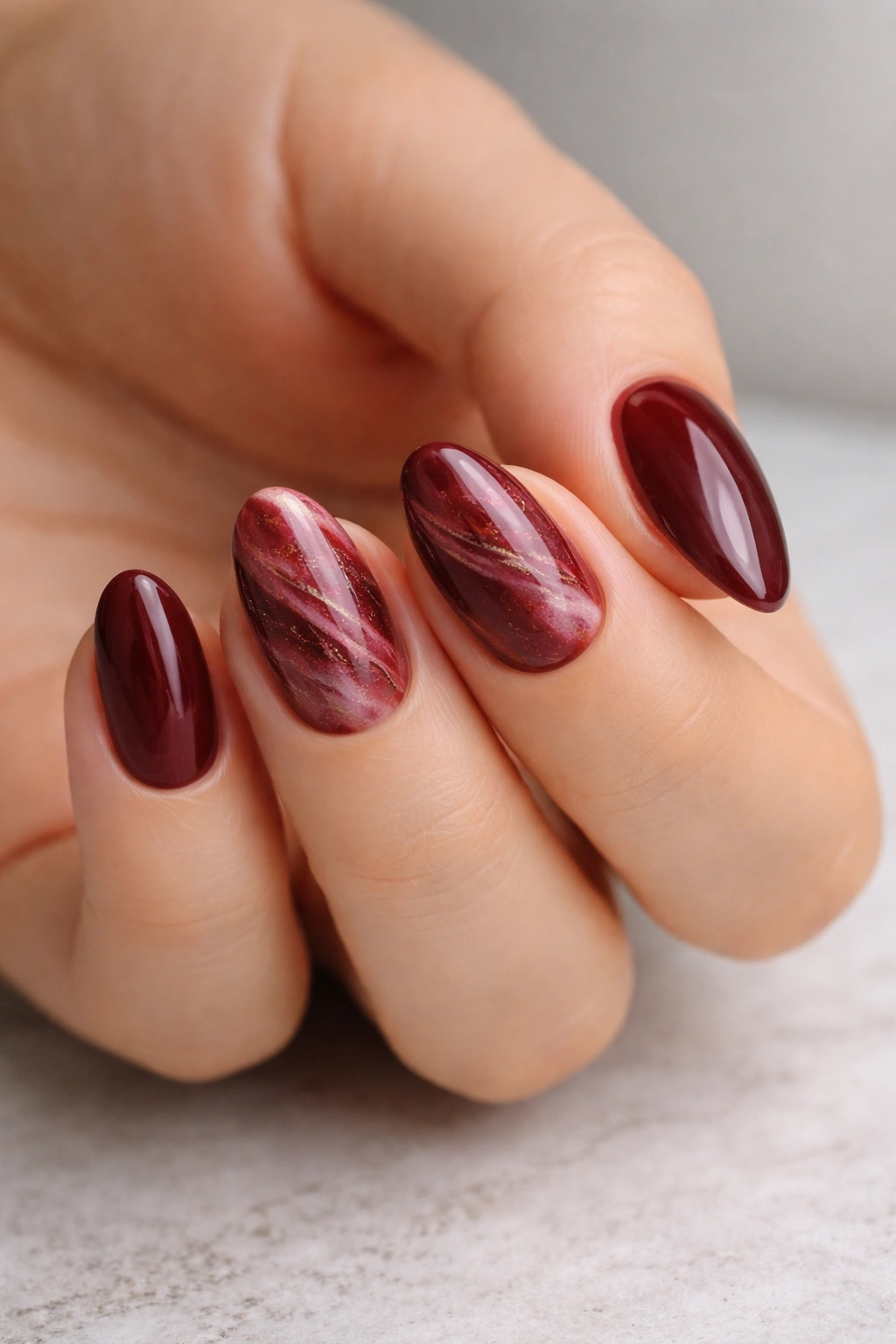 Maroon almond nails with burgundy marble swirls on accent nails