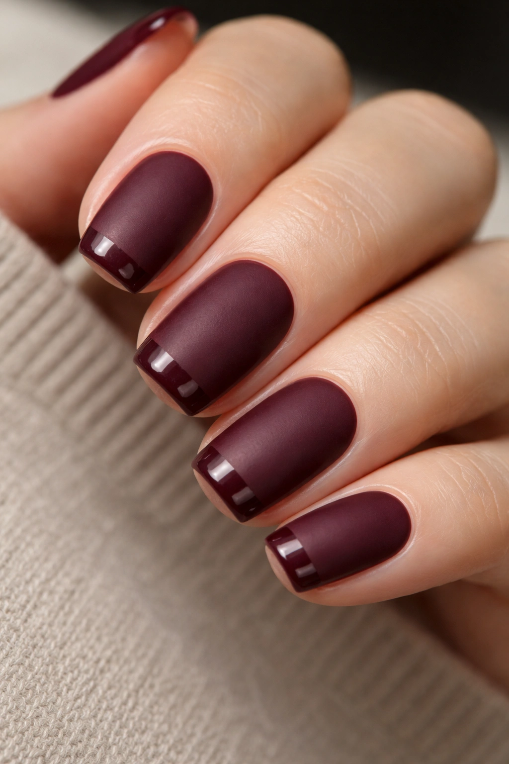 Close-up of burgundy squoval nails with matte body and glossy tips