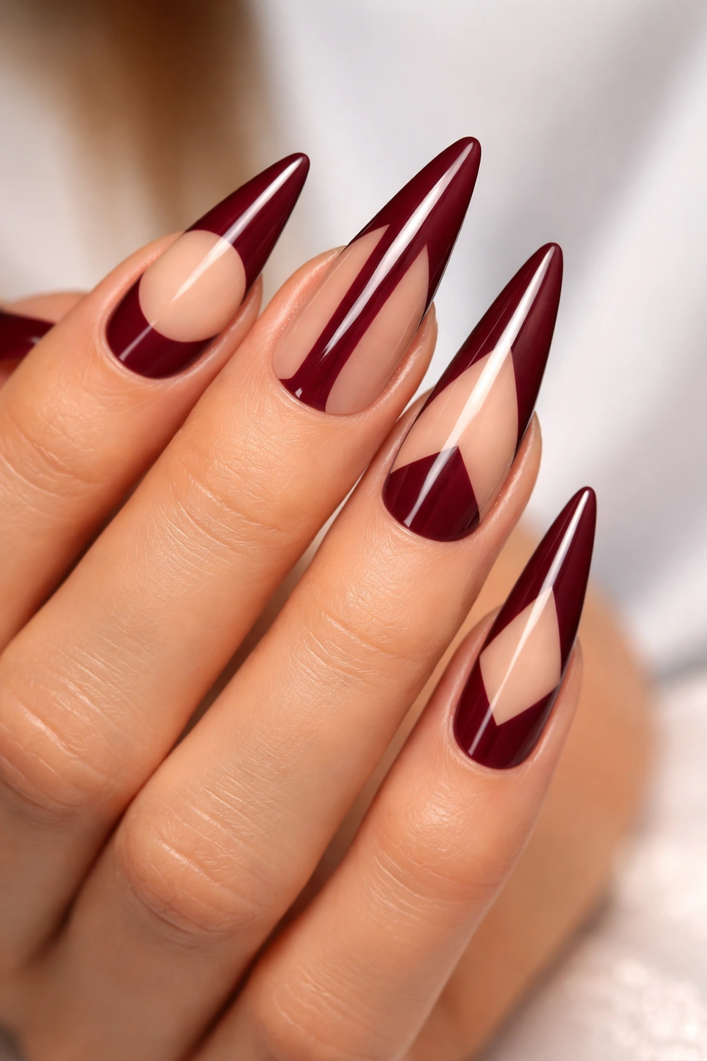 Burgundy stiletto nails with negative space design patterns
