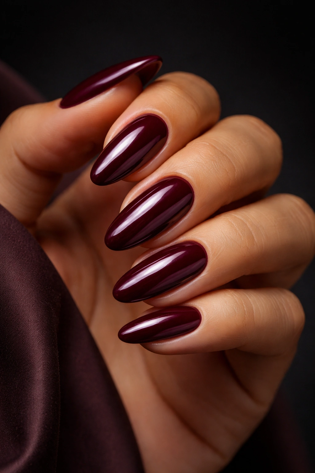 Close-up of deep burgundy nails on olive skin.