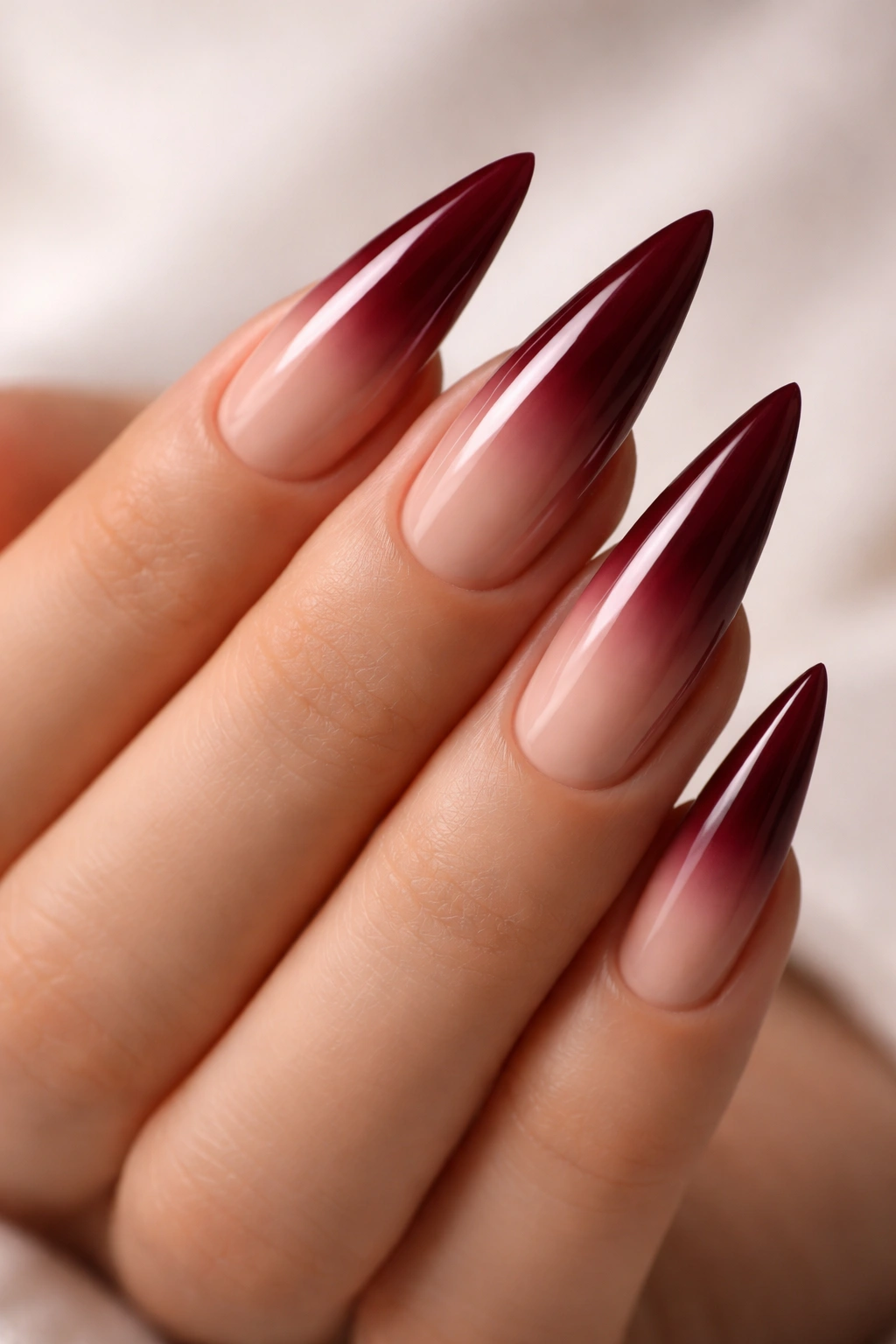 Close-up of burgundy to nude ombre stiletto nails