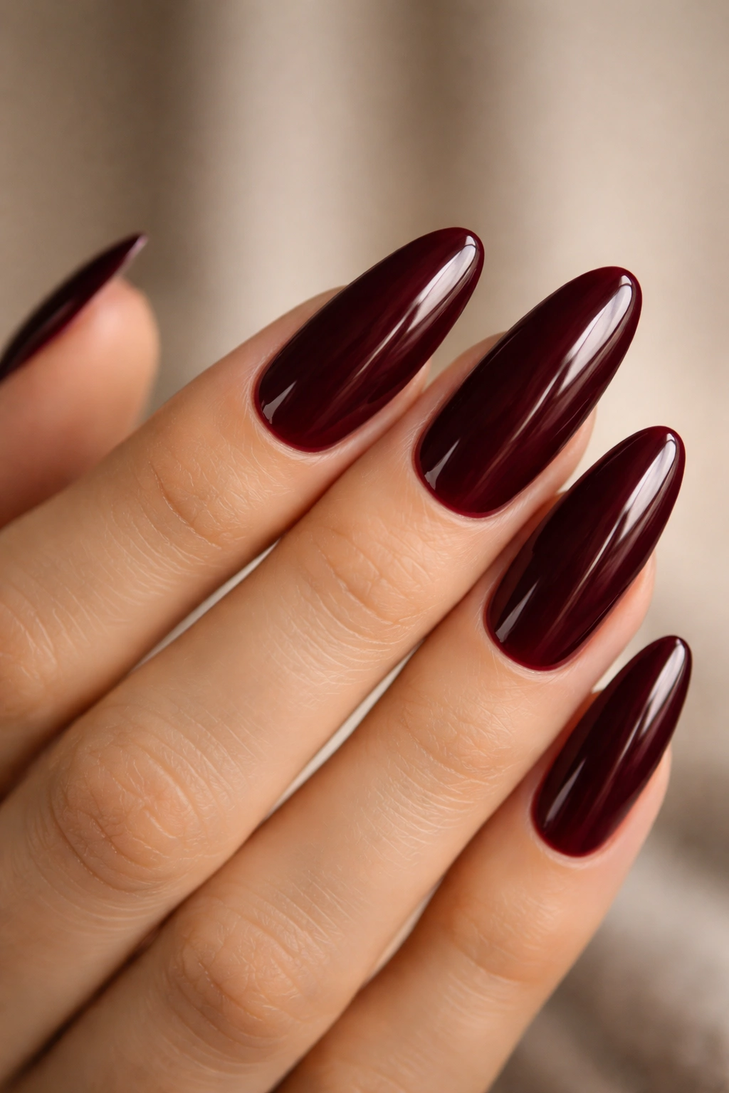 Close-up of deep burgundy long oval nails on hand
