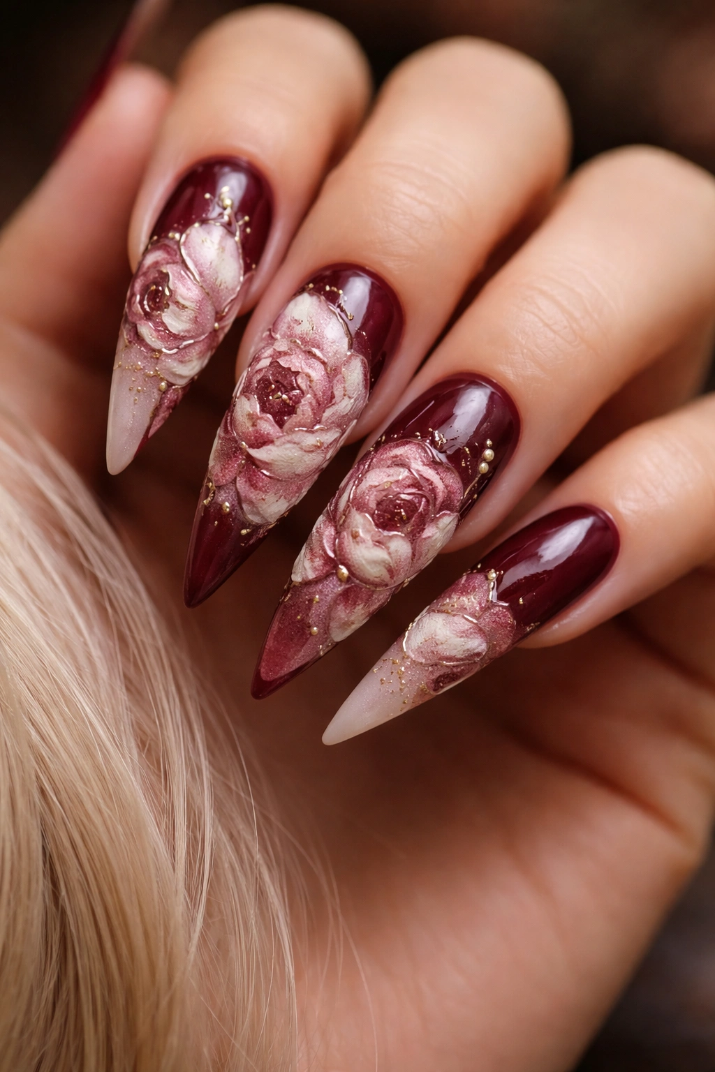 Close-up burgundy stiletto nails with oversized velvet raised peonies