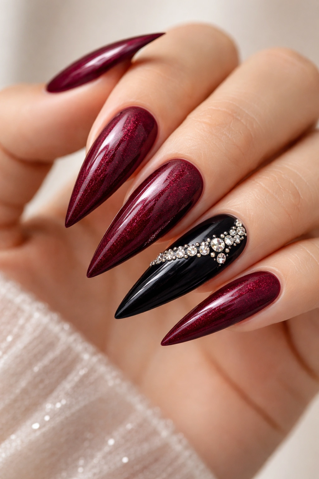 Close-up of burgundy and black rhinestone glitter nails on hands