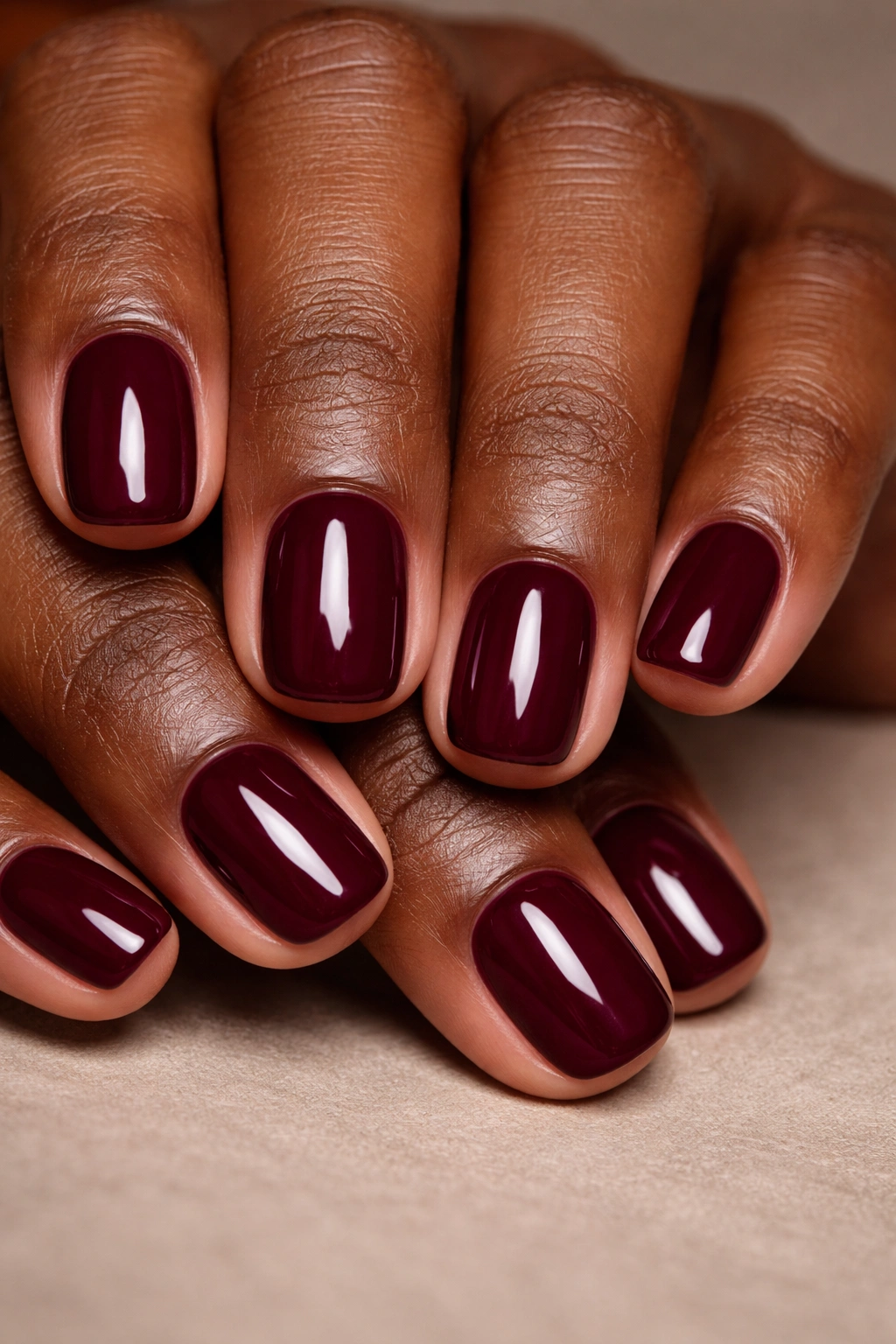 Short burgundy nails on a neutral background