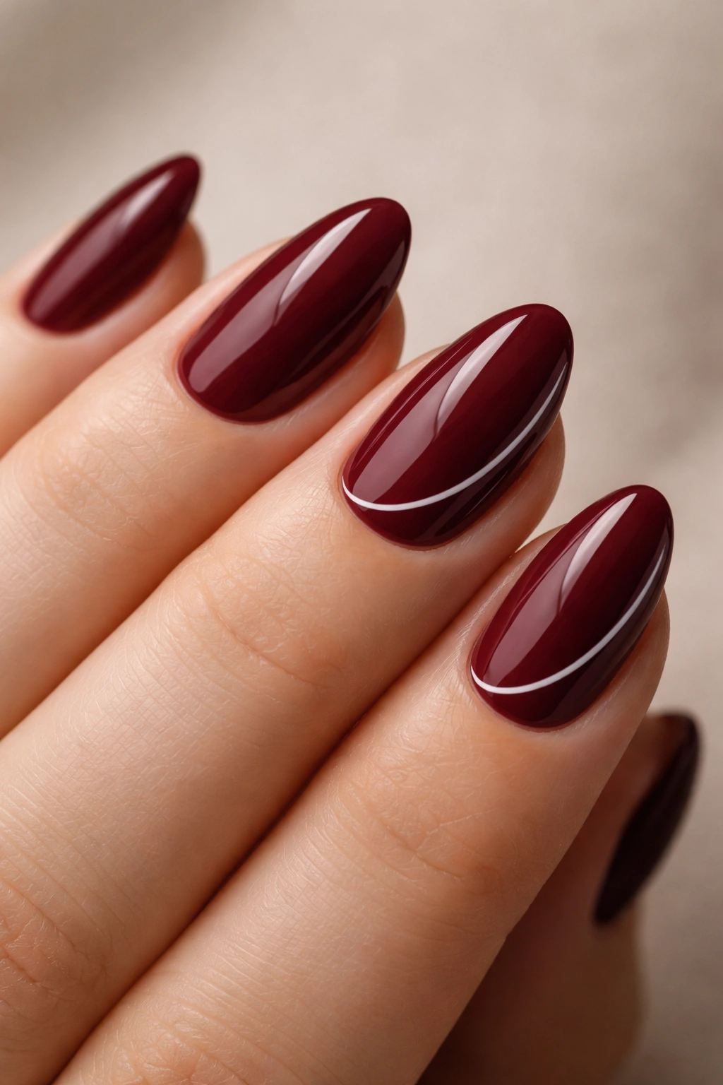 Close-up of burgundy nails with thin white line art on a couple of accent nails.