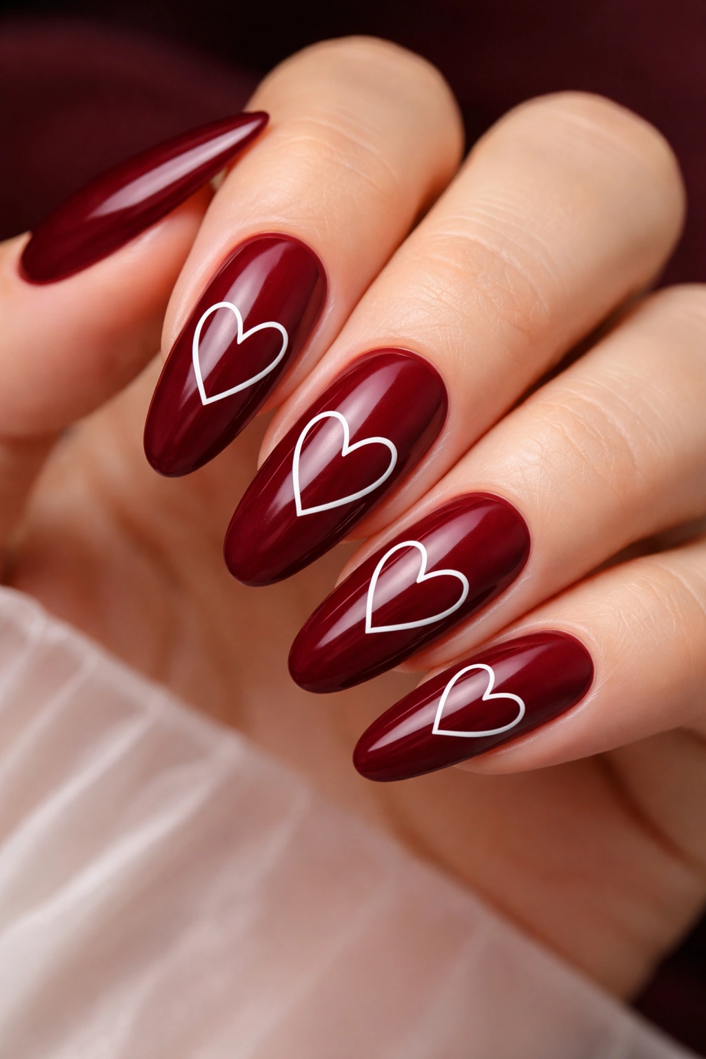 Close-up of burgundy nails with white heart outlines