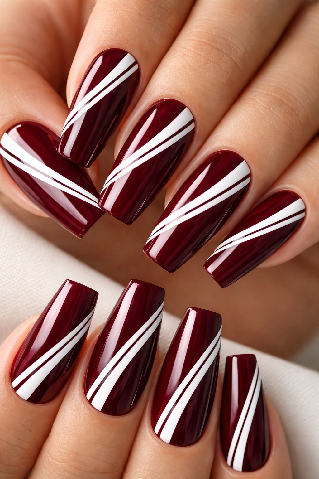 Close-up of burgundy coffin nails with white stripes