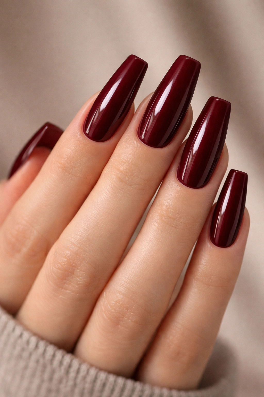 Close-up of medium coffin nails in deep burgundy wine red with glossy finish