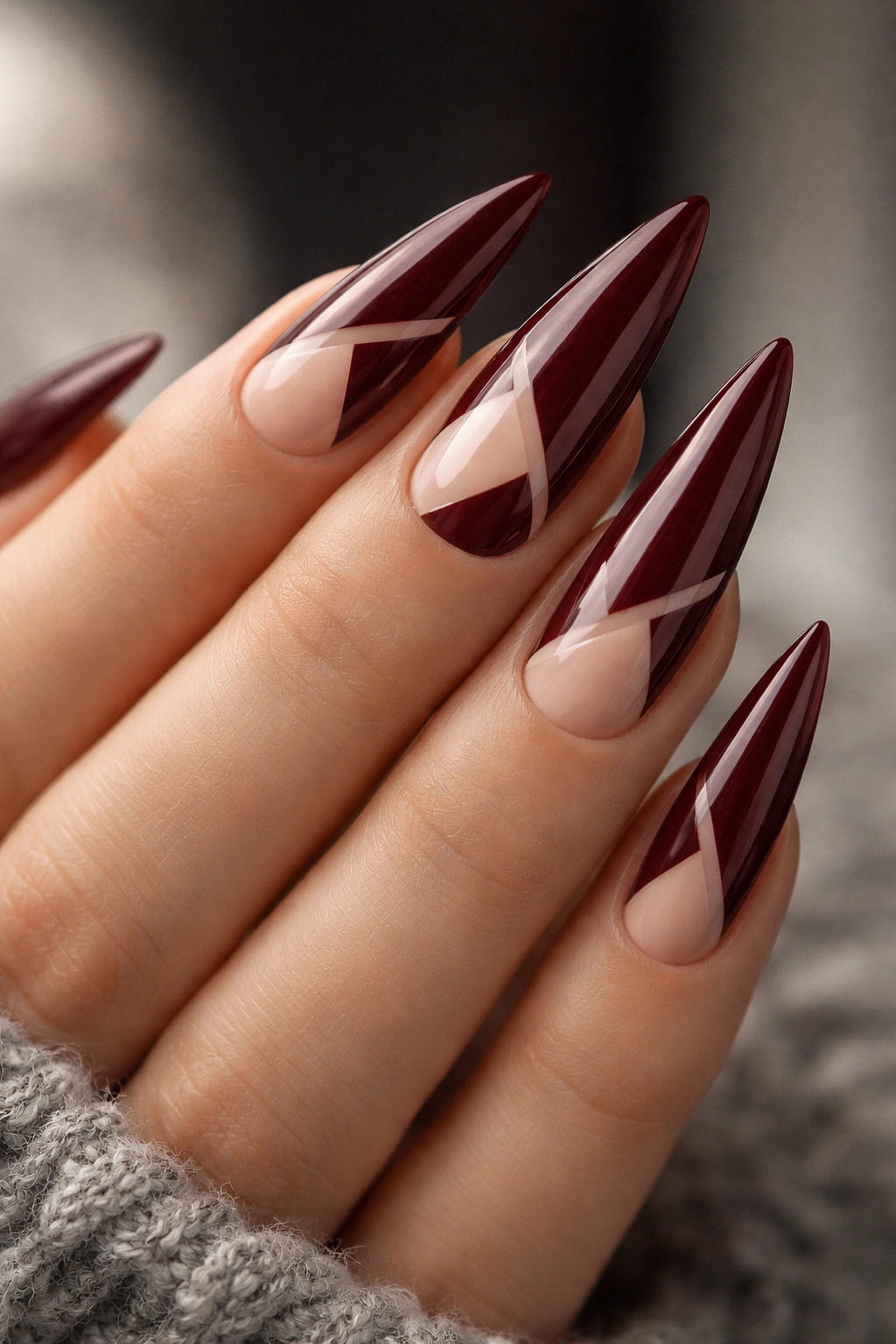Close-up of deep burgundy stiletto nails with negative-space design
