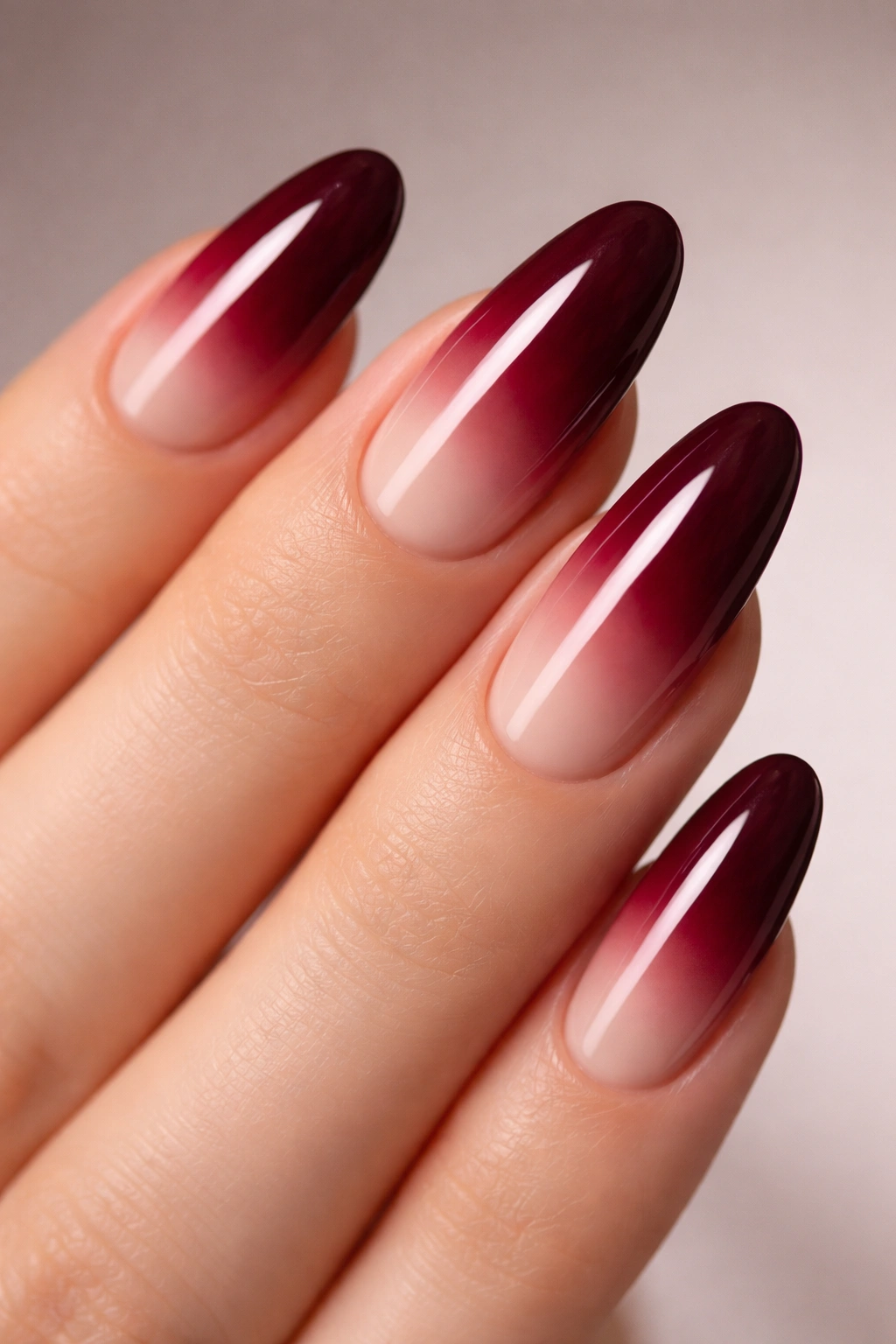 Long oval nails with deep burgundy to nude ombre gradient