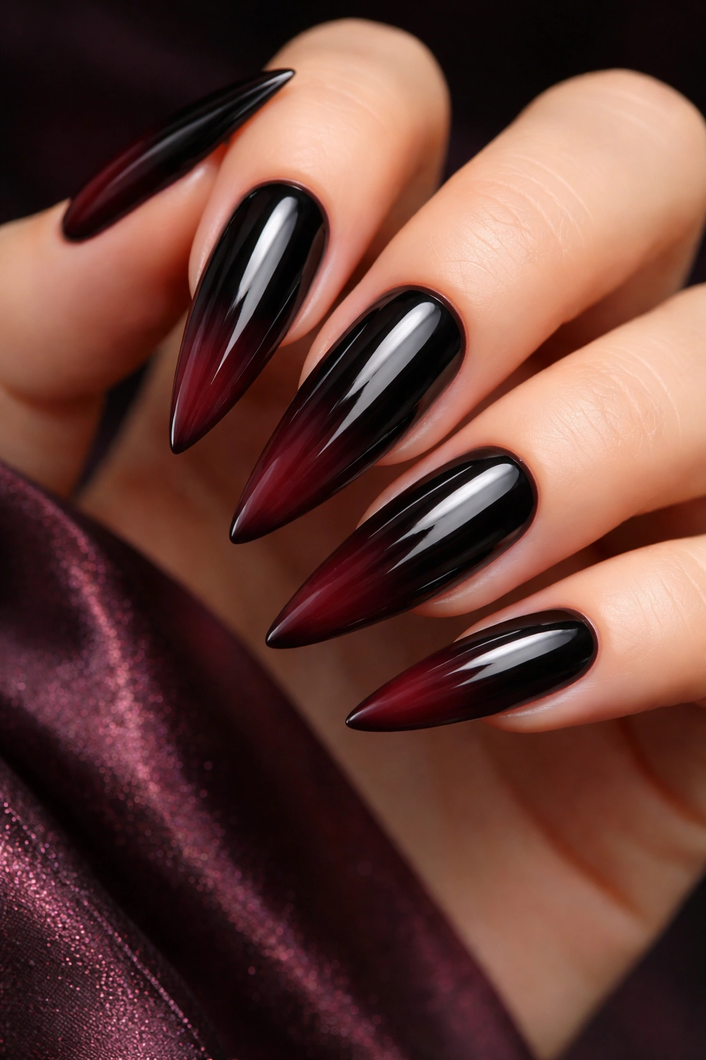 Close-up of black stiletto nails with burgundy wine ombre