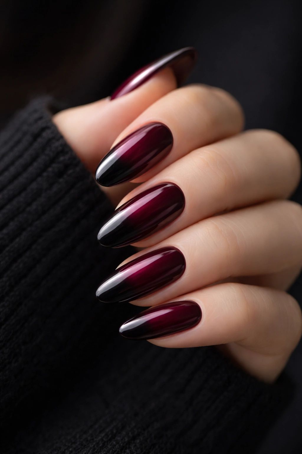 Close-up of burgundy to black ombre on long oval nails with smooth gradient.