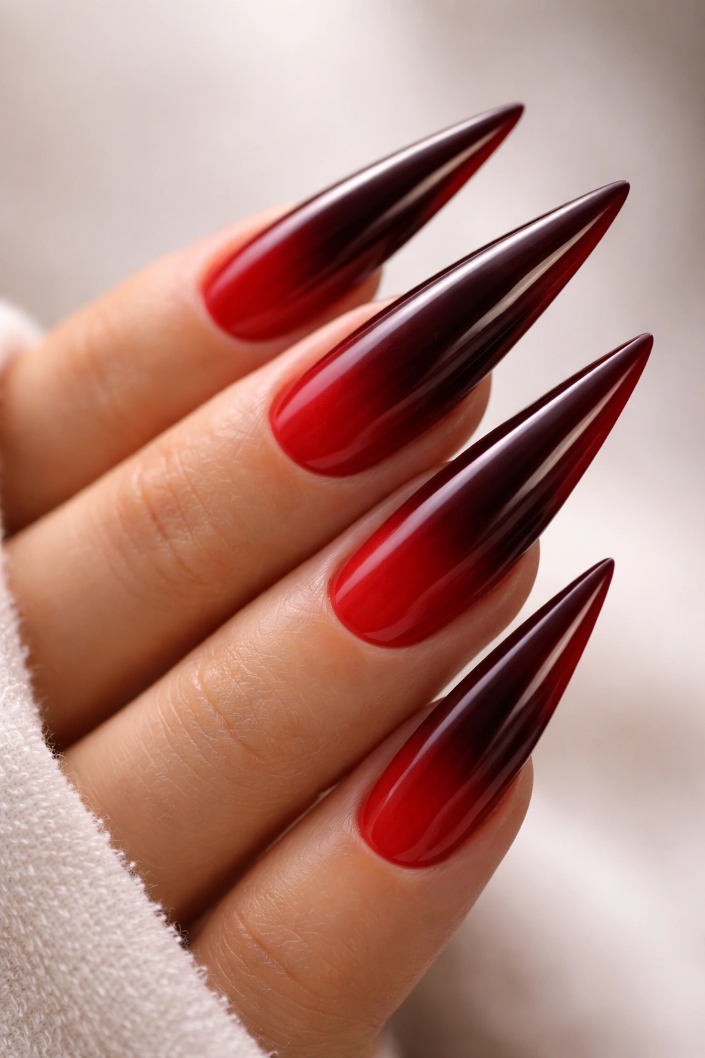 Close-up of burgundy ombré stiletto nails transitioning from deep maroon to bright red