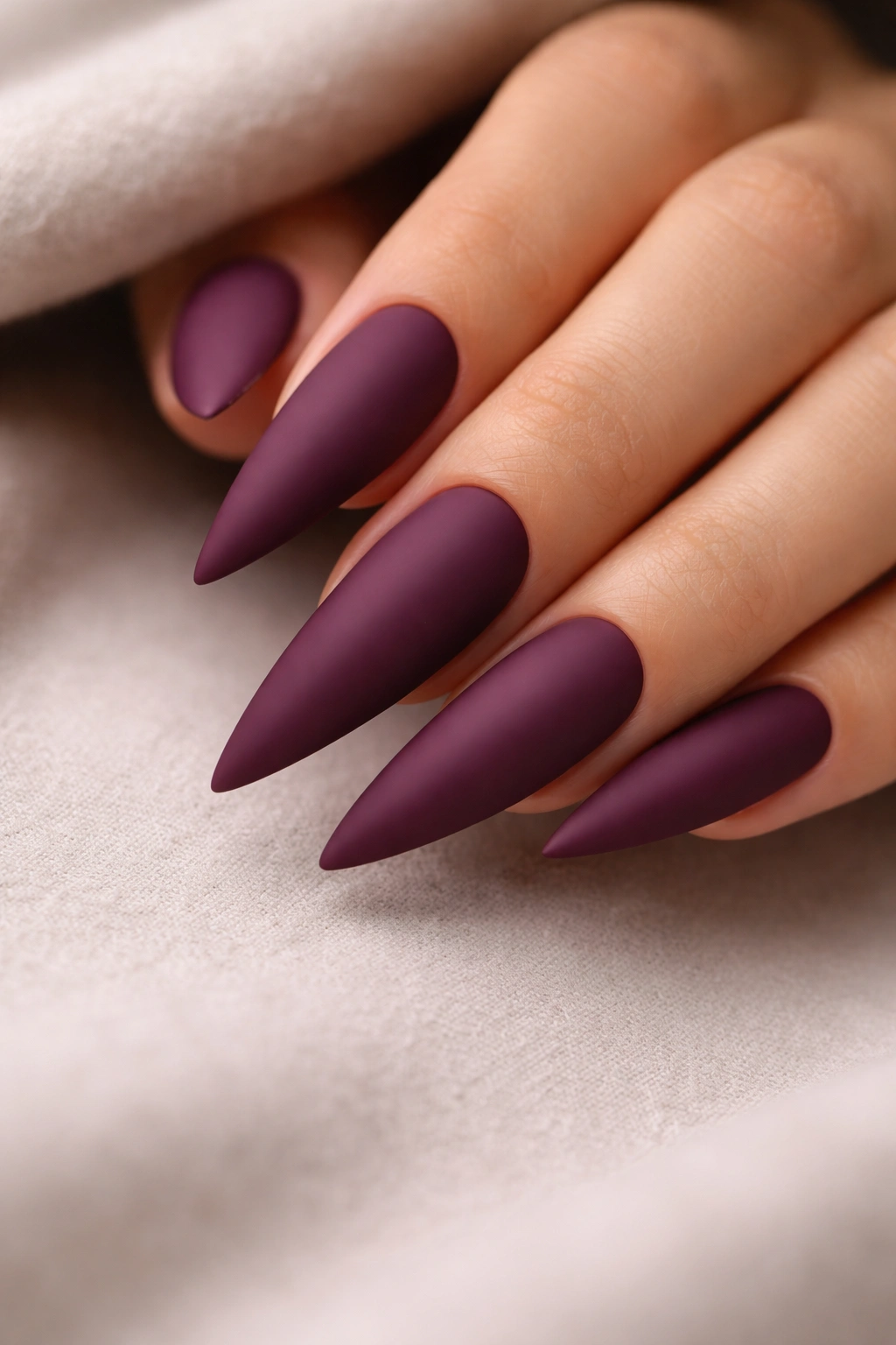 Close-up burgundy-purple matte stiletto nails