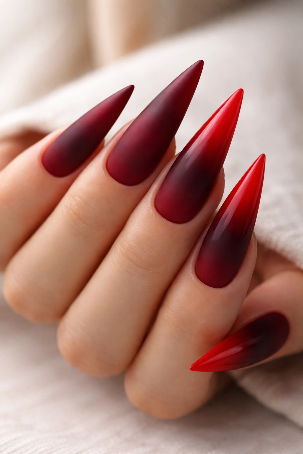 Close-up of stiletto nails with burgundy to red ombre