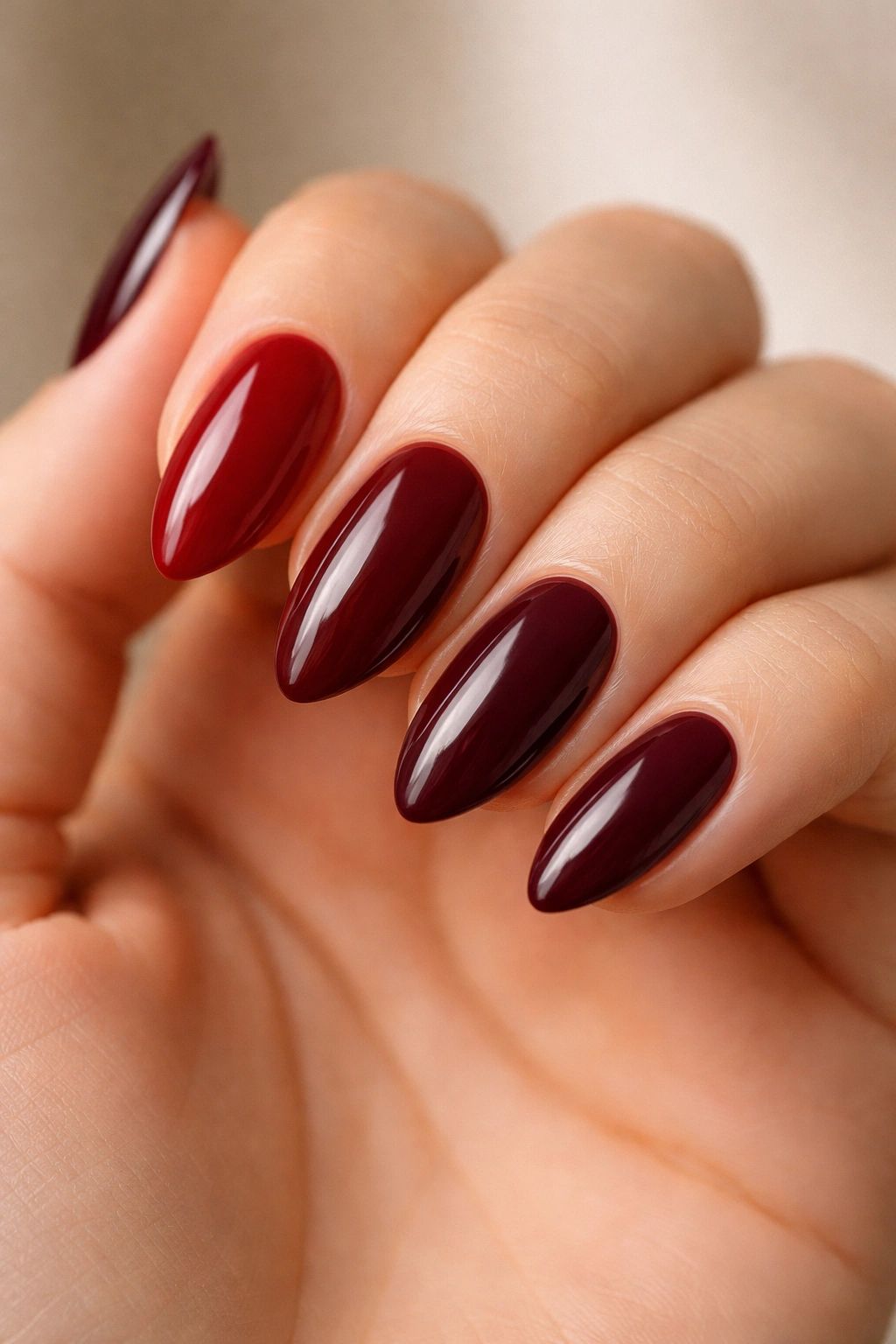 Nails showing multiple burgundy shades with different undertones on a hand