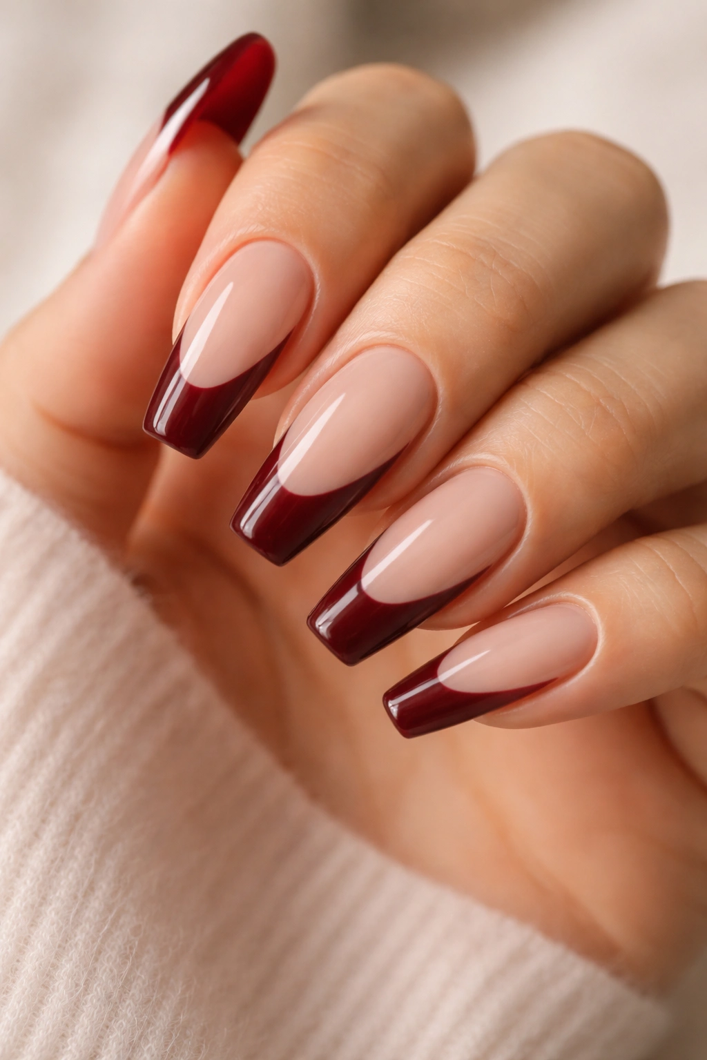 Medium-length ballerina nails with burgundy swoop tips on beige nude base