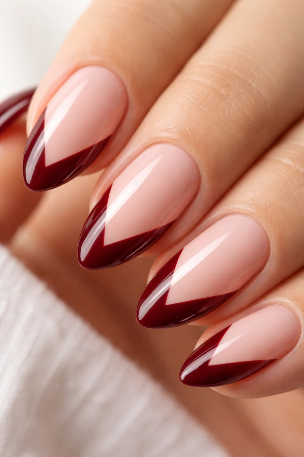 Short almond nail with deep burgundy V-cut tip on nude base