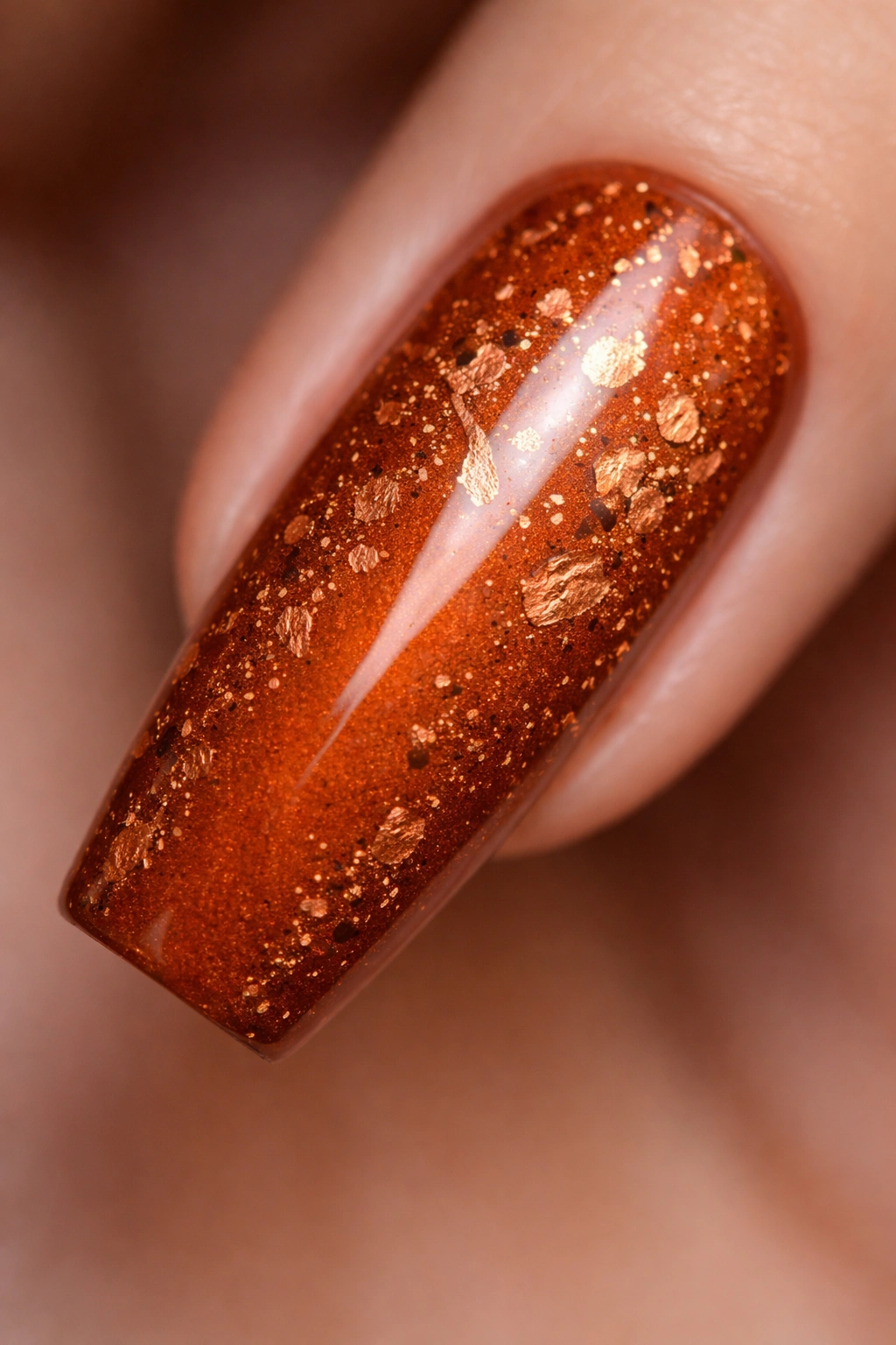 Close-up of burnt orange coffin nail with copper leaf texture on neutral background