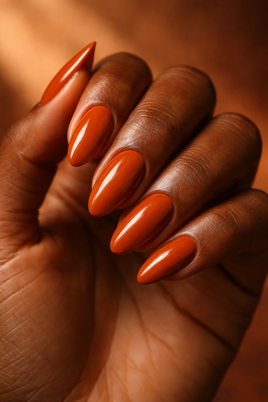 Close-up of dark-skinned hand with burnt orange nails