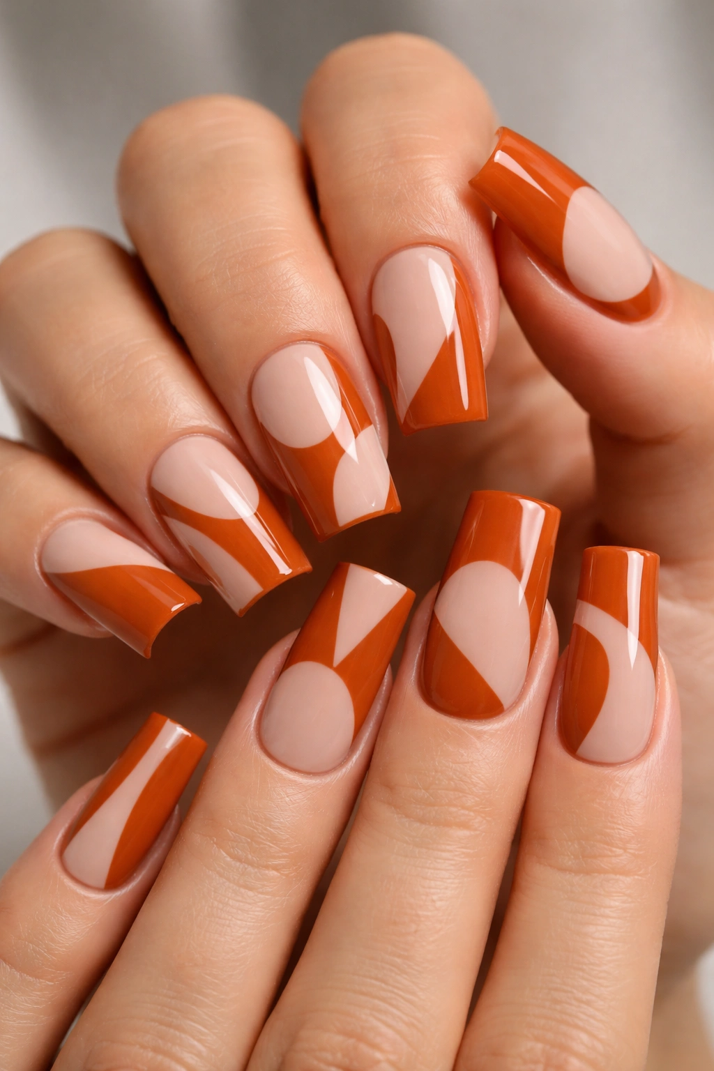 Burnt orange curved duck nails with negative-space geometric shapes