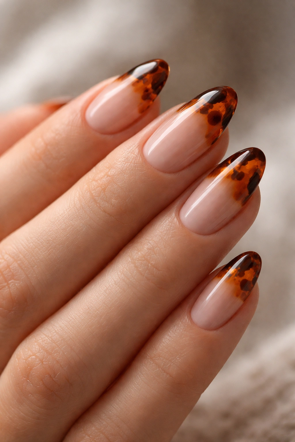 Close-up of burnt orange and brown tortoiseshell tips on short almond nails
