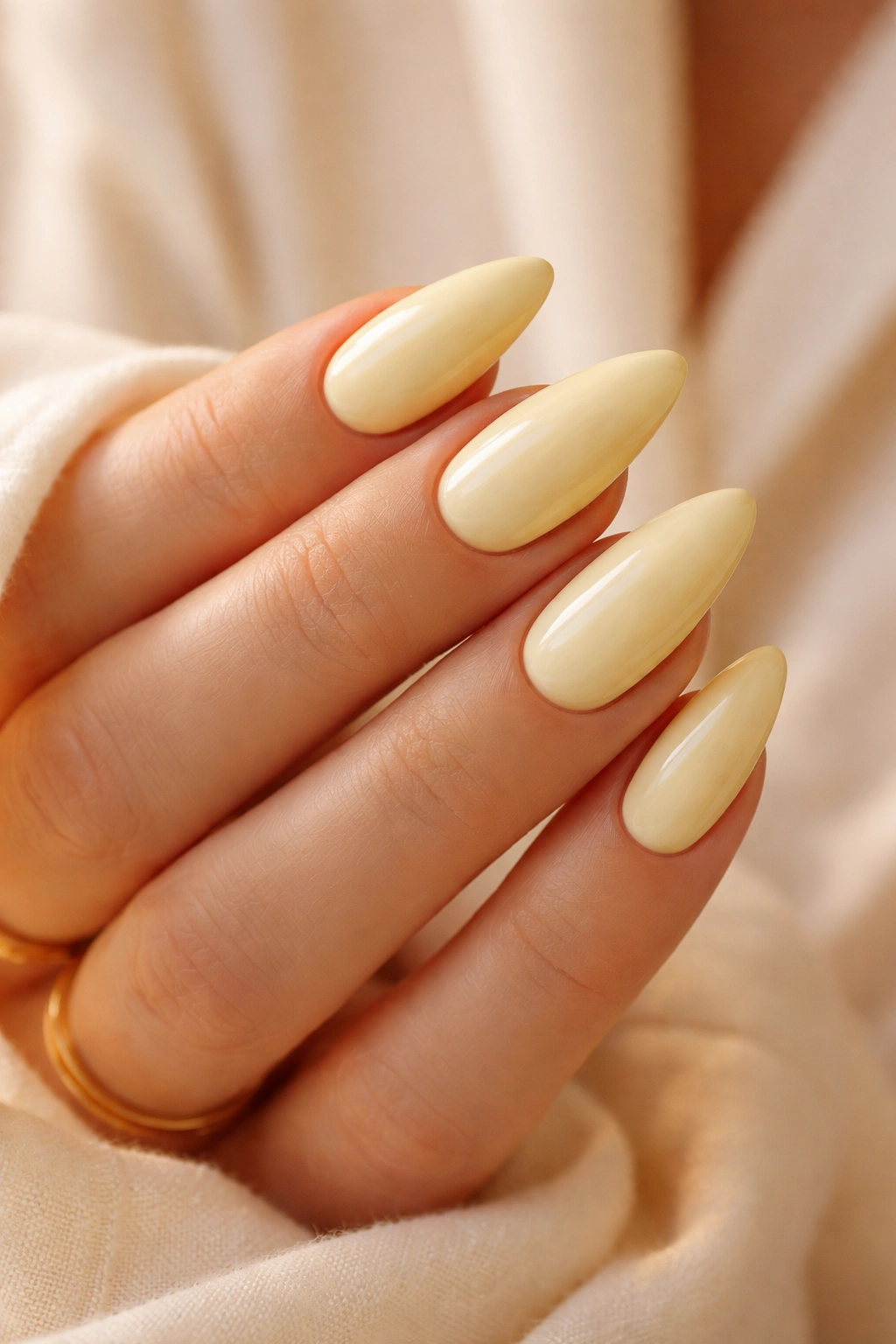 Almond nails painted creamy butter yellow for a warm, neutral look