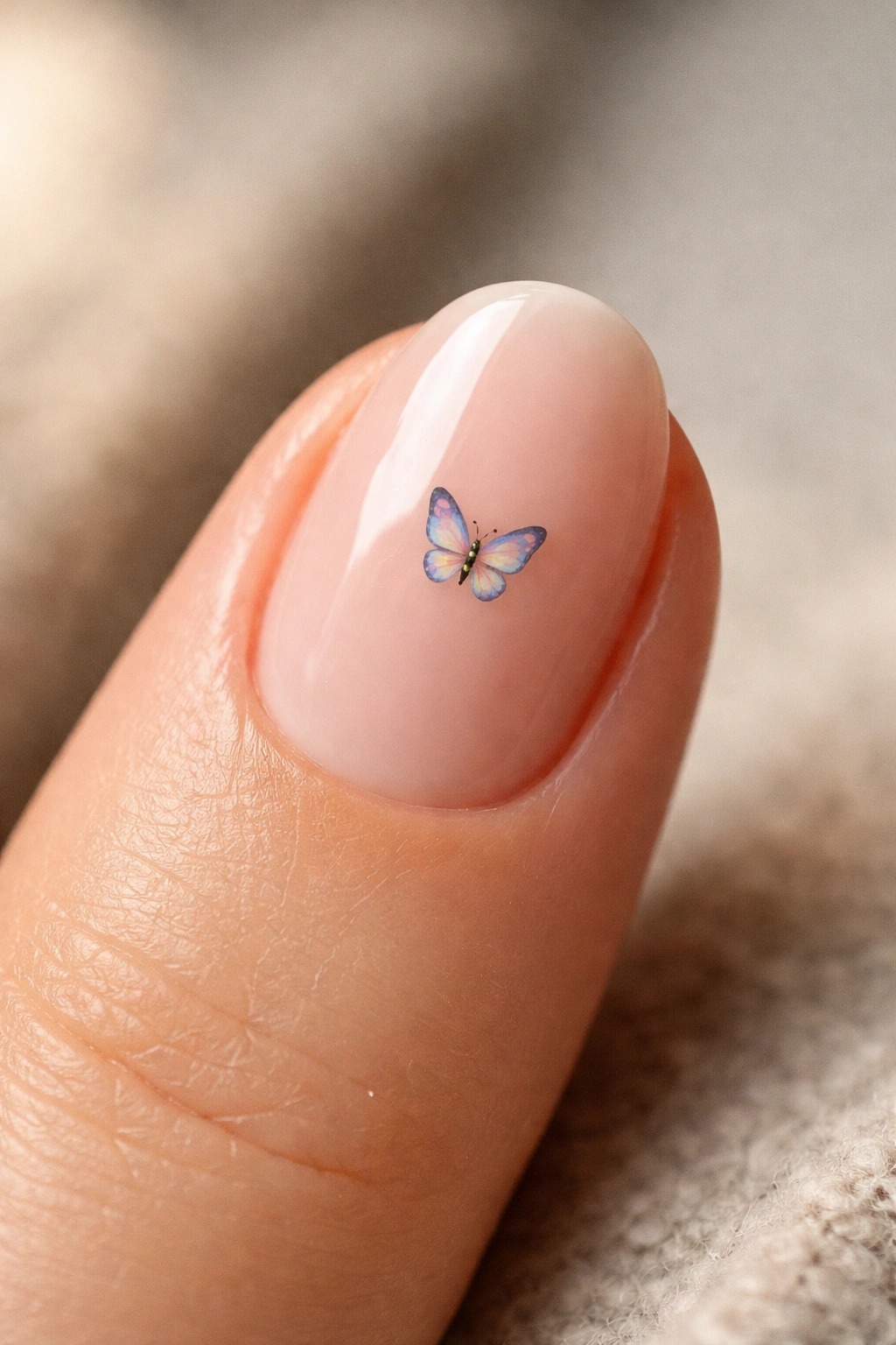 Close-up of a short oval nail with a tiny butterfly motif placed near the center