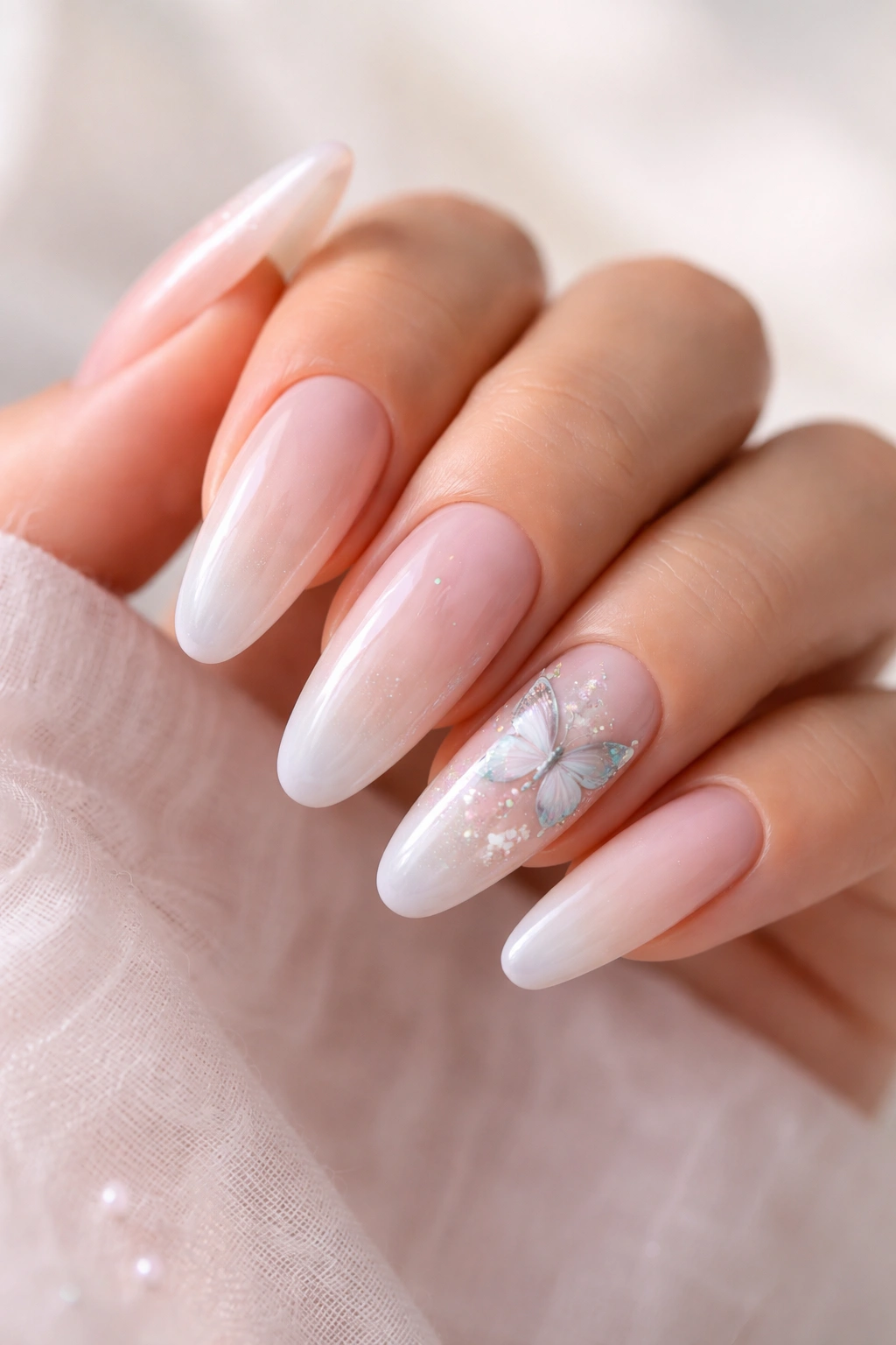 Close-up of a hand with butterfly-accent long oval nails on a pastel base
