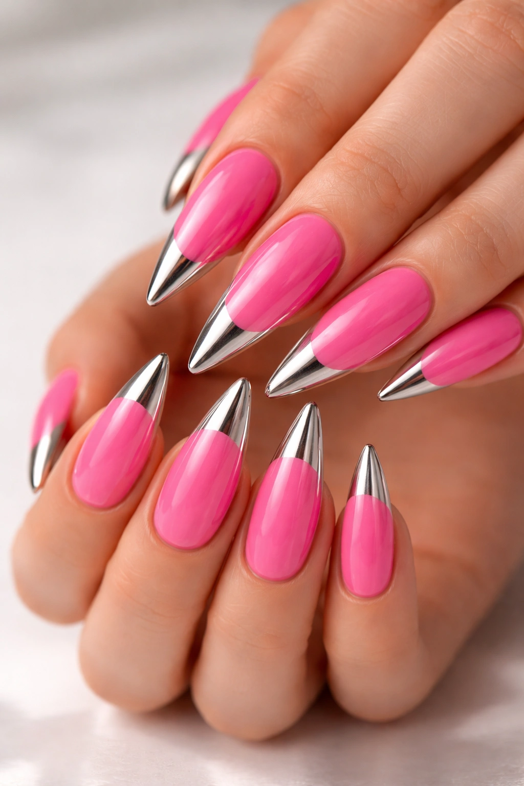 Close-up of candy pink stilettos with metallic toe tips on a reflective surface