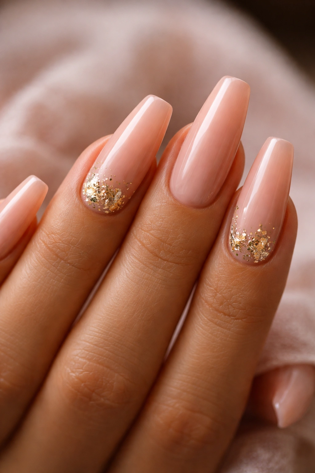 Caramel blush nails with micro gold foil accents on warm skin.