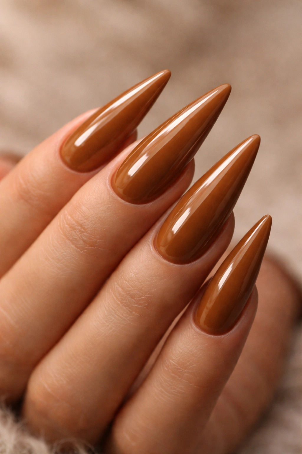 Macro close-up of caramel glazed stiletto nails with high shine