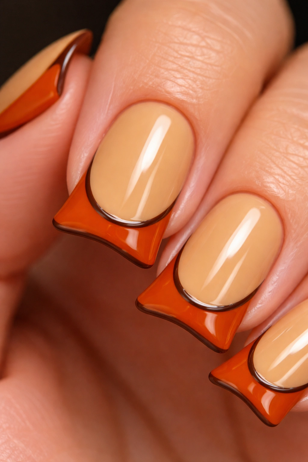 Close-up of a short nail with caramel base, burnt orange duck tip, and brown outline